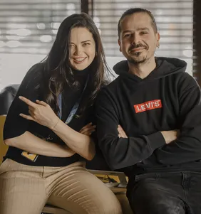 Twee teamleden zitten glimlachend op de rand van een bureau in het kantoor