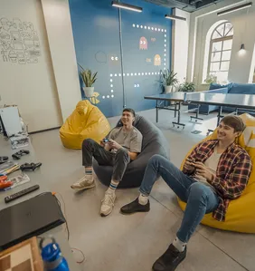 Twee teamleden spelen videogames in zitzakken in de spelkamer van het kantoor met pingpongtafel