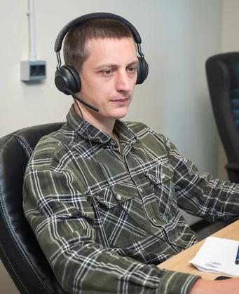 Man met headset en microfoon werkt aan een bureau tijdens een videogesprek
